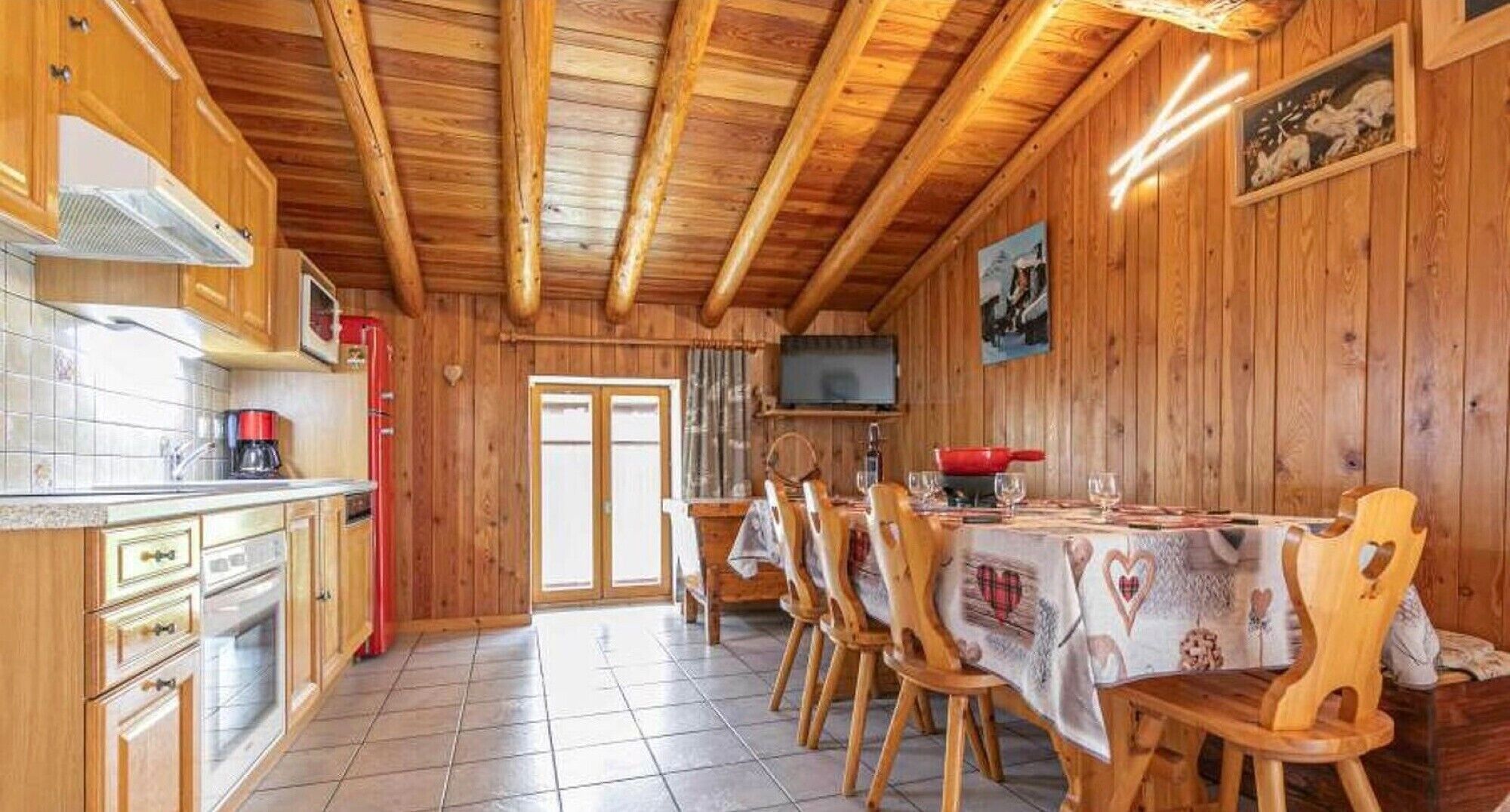 Een houten interieur met een keuken, eethoek en een televisie.