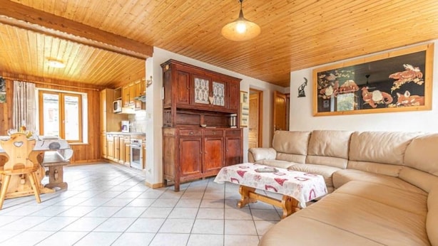 A wooden interior with a sofa, a dining table, and a kitchen area.