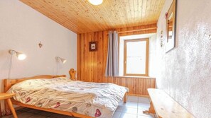 Un dormitorio con paneles de madera, una cama, lámparas de noche, una ventana y un banco.