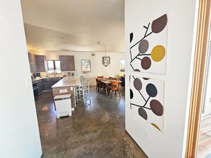 Una cocina moderna con armarios oscuros, una isla central y un comedor con sillas y una mesa.