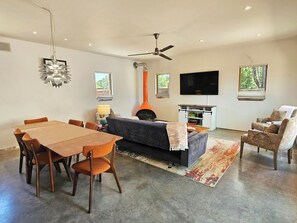 Una sala de estar moderna con comedor, chimenea, ventilador de techo y televisor de pantalla plana.