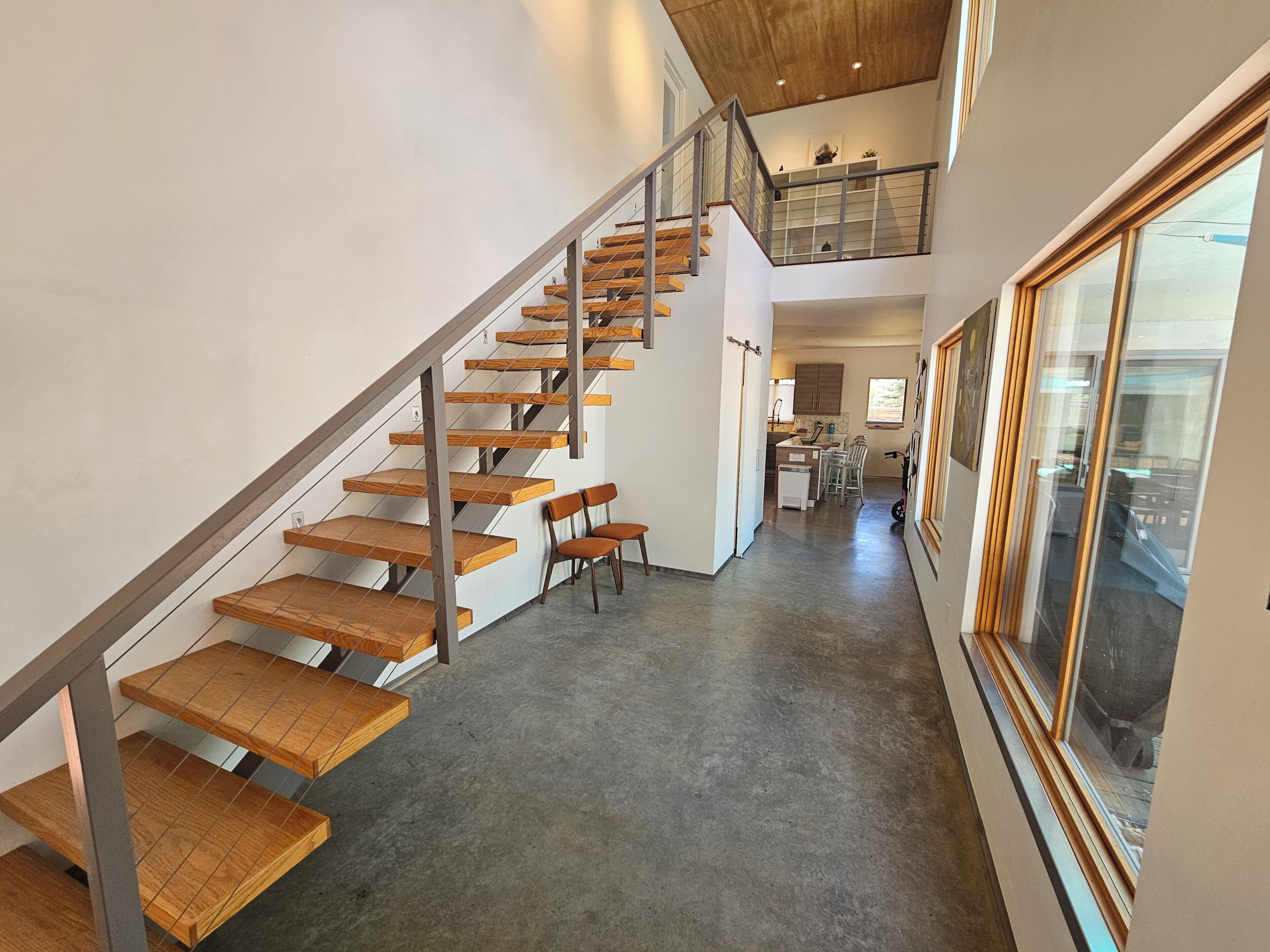 A multi-level interior with a wooden staircase, a dining area, and a kitchen.