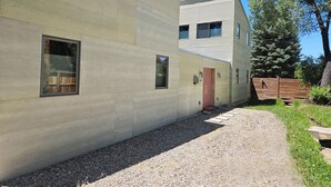 A modern building with a concrete facade, a gravel pathway, and a wooden fence. - Private Luxury Modern Design with NM charm: Gourmet Kitchen & Spa Bath! (Taos)