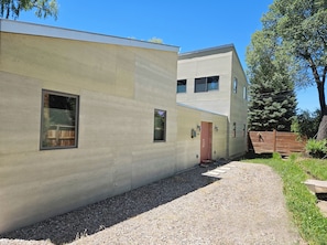 A modern building with a concrete facade, a gravel pathway, and a wooden fence. - Private Luxury Modern Design with NM charm: Gourmet Kitchen & Spa Bath! (Taos)