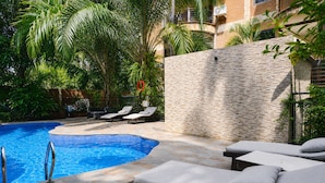 Una piscina con sillas de descanso y un muro de piedra.