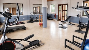 Un gimnasio con máquinas de cardio, pesas y espejos.