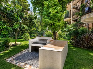 A courtyard with a fire pit, a seating area, and lush greenery. - 2-bedroom apartment with Garden view (Accra)
