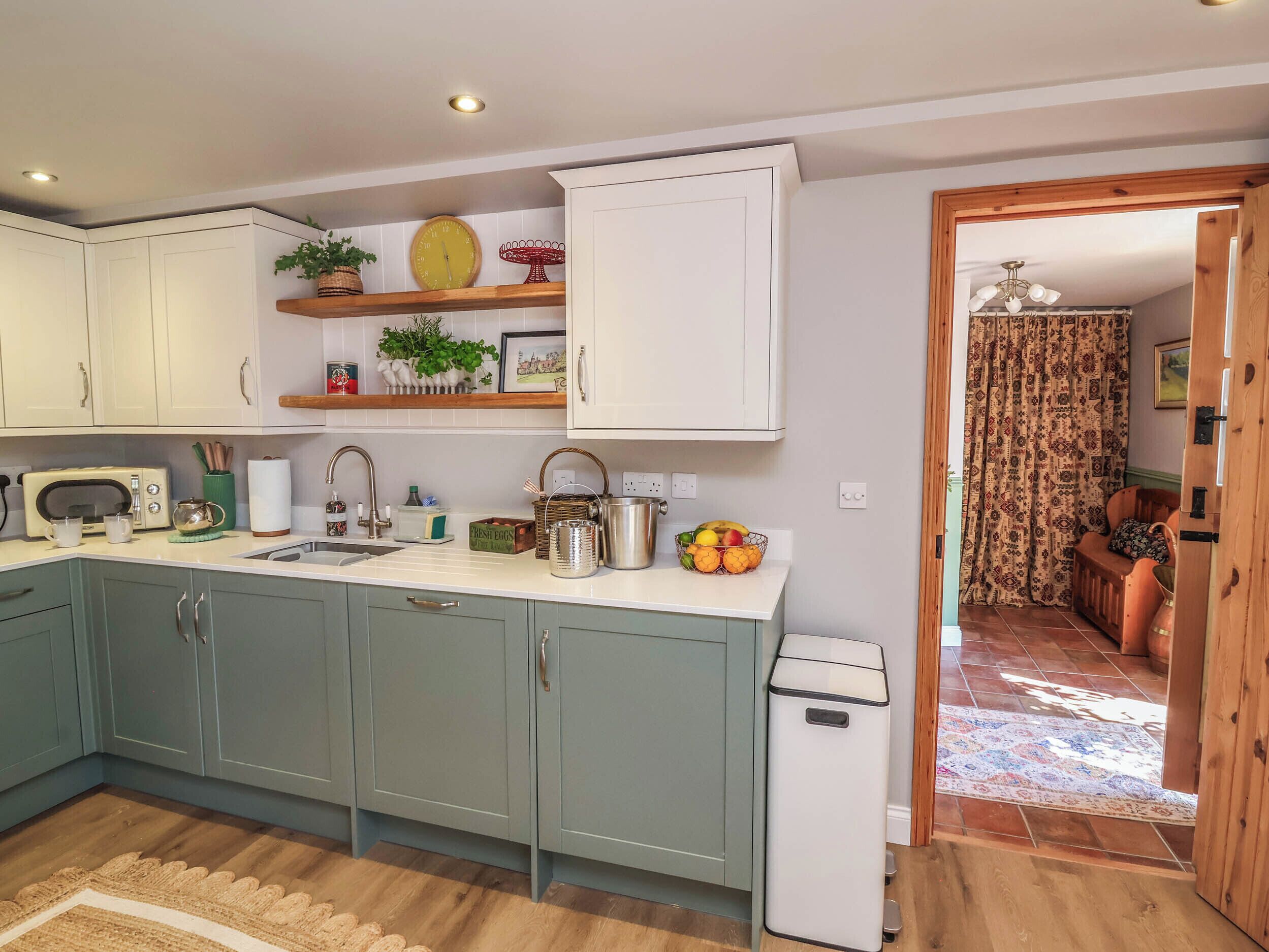 A compact kitchen with a sink, a microwave, and a small trash bin.