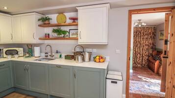 A compact kitchen with a sink, a microwave, and a small trash bin.