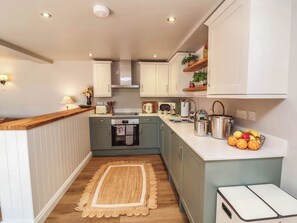 Cocina compacta con horno integrado, un lavamanos y una pequeña zona de encimera.