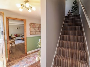 A staircase with striped carpeting and a wooden door leading to a room with a green wall and a world map. - Captains Barn (Tiverton)
