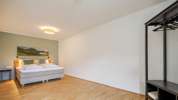 Un dormitorio moderno con una cama, una mesita de noche, un estante en la pared y un cuadro.