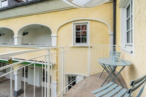 Ein Balkon mit Tisch und Stühlen, weißen Geländern und einem Fenster mit Aussicht.