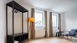 Una habitación moderna con una cama litera, una lámpara de pie, una silla y una ventana con cortinas.