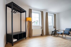 Ein modernes Zimmer mit Etagenbett, Stehlampe, Sessel und einem fenster mit Vorhängen.