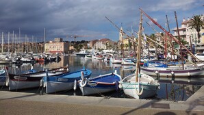 A marina with various boats docked, a crane in the background, and buildings along the waterfront. - Stellamare (Sanary-sur-Mer)