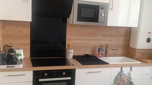 A modern kitchen with a built-in oven, microwave, and a black range hood. - Stellamare (Sanary-sur-Mer)