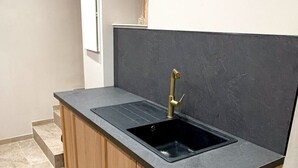 Cocina con encimera negra, grifo dorado y muebles de madera.