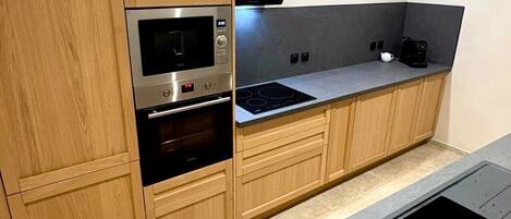 Eine moderne Küche mit Holdekor-Schränken, einem Backofen, einem Kochfeld und einer schwarzen Arbeitsplatte.