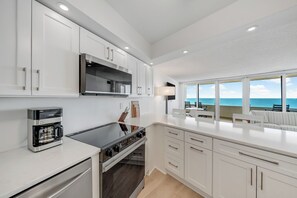 A modern kitchen with white cabinets, a built-in oven, and a coffee maker. - Antigua 1103 by Seaside Vacations & Sales (Ocean City)