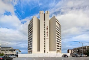 A tall, modern building with the name 'ANTIGUA' on its facade, featuring a symmetrical design with a central vertical element. - Antigua 1103 by Seaside Vacations & Sales (Ocean City)