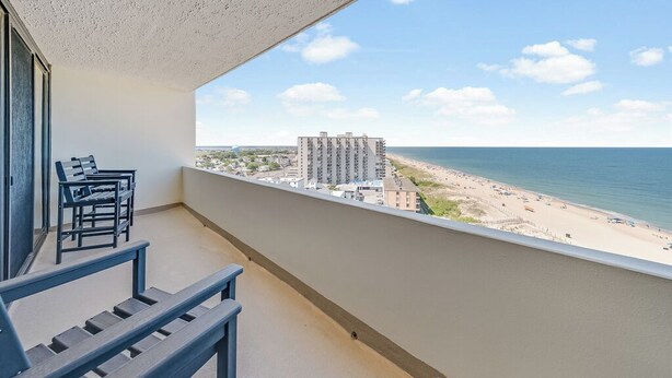 Uma varanda com vista para uma praia e um prédio alto.