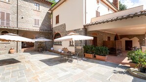 A courtyard with stone flooring, outdoor seating, and potted plants.