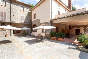 Un patio con suelo de piedra, mobiliario exterior y plantas en macetas.