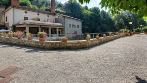 A stone building with a tiled roof, a covered porch, and a gravel courtyard.