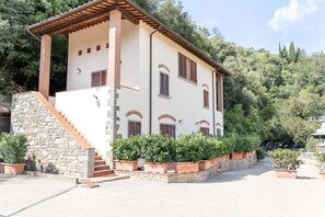 A two-story building with a stone staircase and a wooden roof, surrounded by greenery. - Apartment 9 with Balcony – Residence Ferriera with Pool (Loro Ciuffenna)