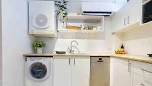 Een kleine keuken met een wasmachine, vaatwasser en een klein spoelgedeelte.