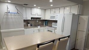 Une cuisine moderne avec des meubles blancs, un îlot central et un réfrigérateur.