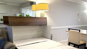A bedroom with a bed, a desk, a chair, and a lamp.