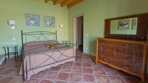 A bedroom with a bed, a wooden dresser, a small table, and two wall-mounted lamps. - Room 'Camera Matrimoniale' with Shared Terrace, Wi-Fi and Air Conditioning (Cavriana)