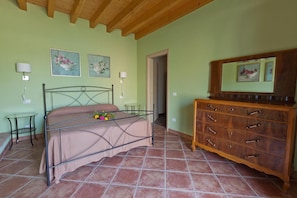 Ein Schlafzimmer mit einem Bett, einem hölzernen Schminktisch, einem kleinen Tisch und zwei Wandleuchten.