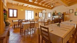 A dining area with wooden tables and chairs, a ceiling fan, and a brick wall. - Room 'Camera Matrimoniale' with Shared Terrace, Wi-Fi and Air Conditioning (Cavriana)
