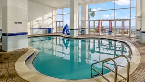 An indoor swimming pool with a view of the ocean through large windows. - Ocean-view escape w/ pools, hot tub & beach access (Panama City Beach)