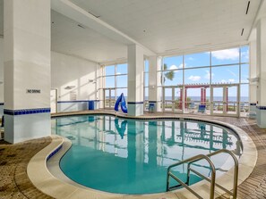 Ein Hallenbad mit Blick auf den Ozean durch große Fenster.