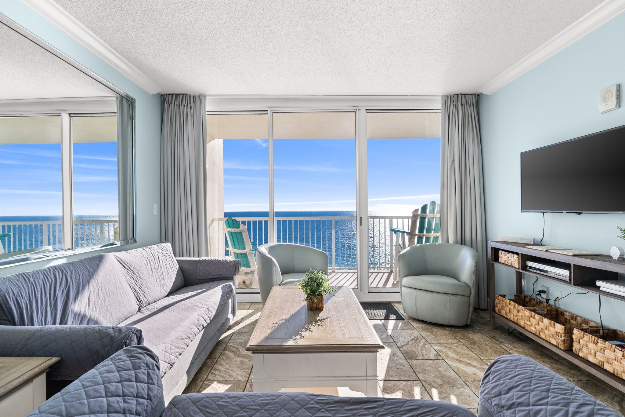 A balcony with a view of the sea, a sofa, a coffee table, and a TV.