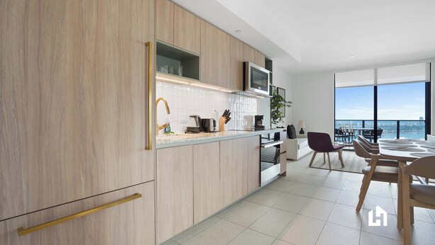 Une cuisine moderne avec des meubles en bois, un four à micro-ondes et un coin repas offrant une vue sur la ville.
