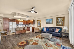 A modern living room with a black leather sofa, a patterned rug, and a dining area with a round table and chairs. - Beach Retreat w/ Balcony & Resort Amenities (Panama City Beach)