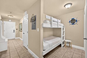 A bedroom with bunk beds, a small table, and a wall-mounted mirror. - Beach Retreat w/ Balcony & Resort Amenities (Panama City Beach)