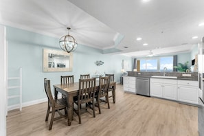 A spacious kitchen with a dining area, white cabinetry, and a large window offering a view. - 20th Floor Beachfront Retreat | Sleeps 8 (Panama City Beach)