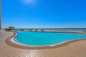 A swimming pool with a sunshade, lounge chairs, and a view of the sea. - 20th Floor Beachfront Retreat | Sleeps 8 (Panama City Beach)