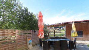 An outdoor patio with a table and chairs, a wooden fence, and a yellow umbrella. - Appartement - Les P'tits Loups, (Courtedoux), by Interhome (Courtedoux)