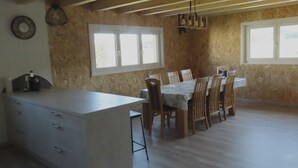 A spacious kitchen with a dining area, wooden ceiling beams, and large windows. - Appartement - Les P'tits Loups, (Courtedoux), by Interhome (Courtedoux)