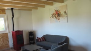 A living room with a sofa, a coffee table, a fireplace, and a painting on the wall. - Appartement - Les P'tits Loups, (Courtedoux), by Interhome (Courtedoux)