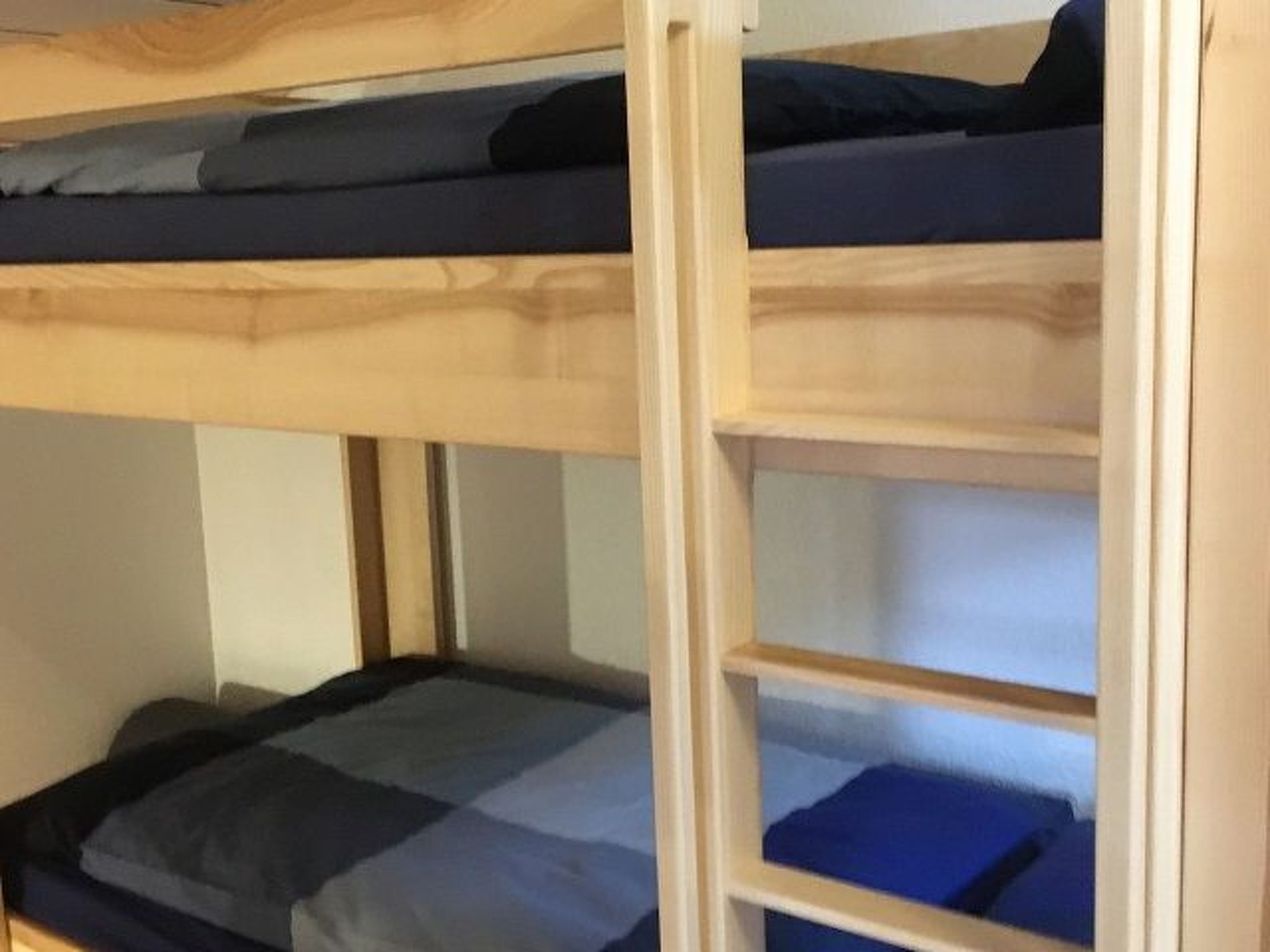 Een stapelbed met een onderbed en een bovenbed, beide met blauw beddengoed.