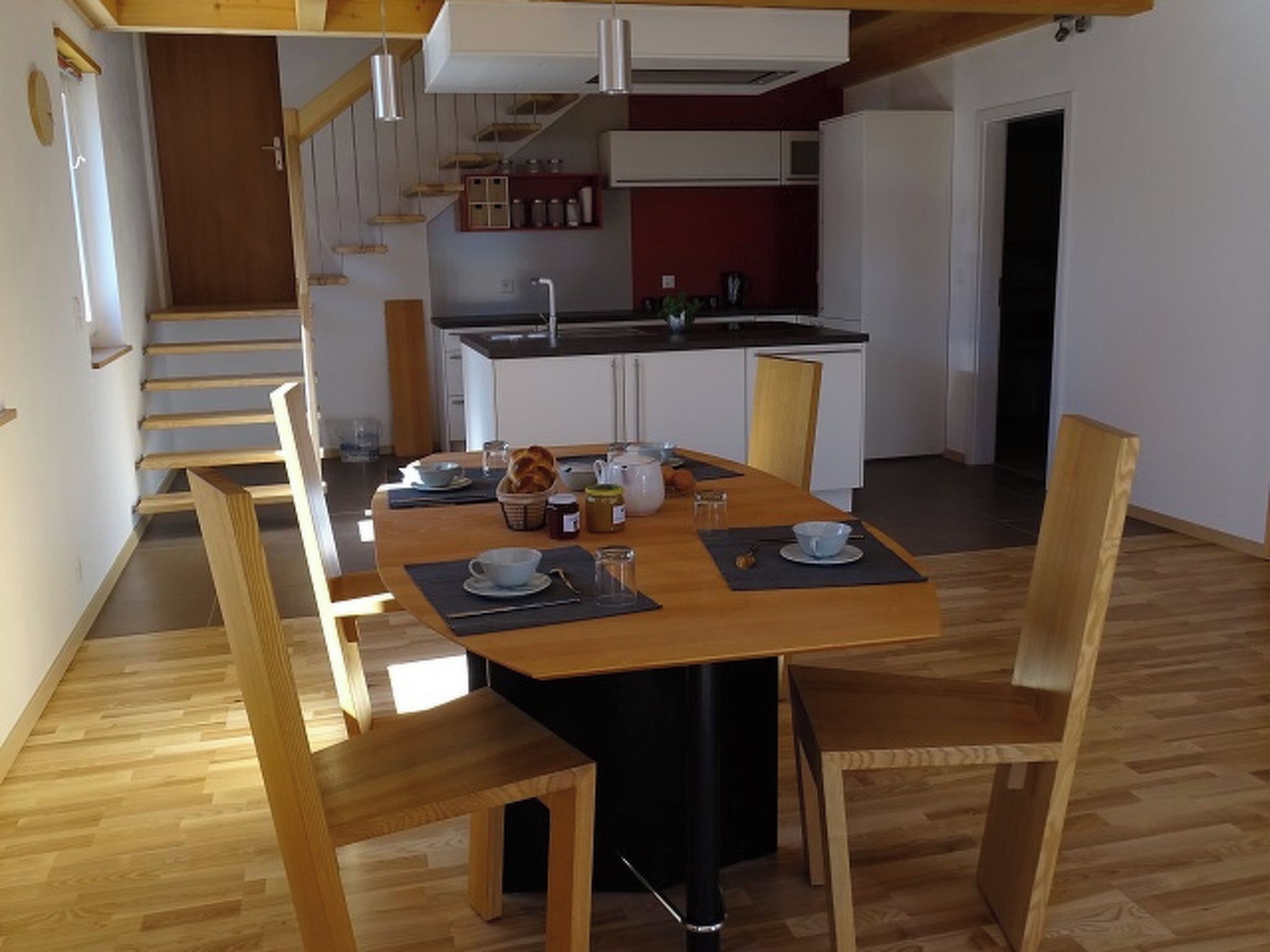 A dining area with a wooden table, chairs, and a kitchen in the background.