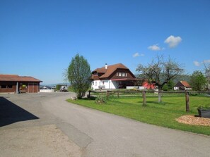 A residential area with a paved driveway leading to a house with a red roof and white walls.
